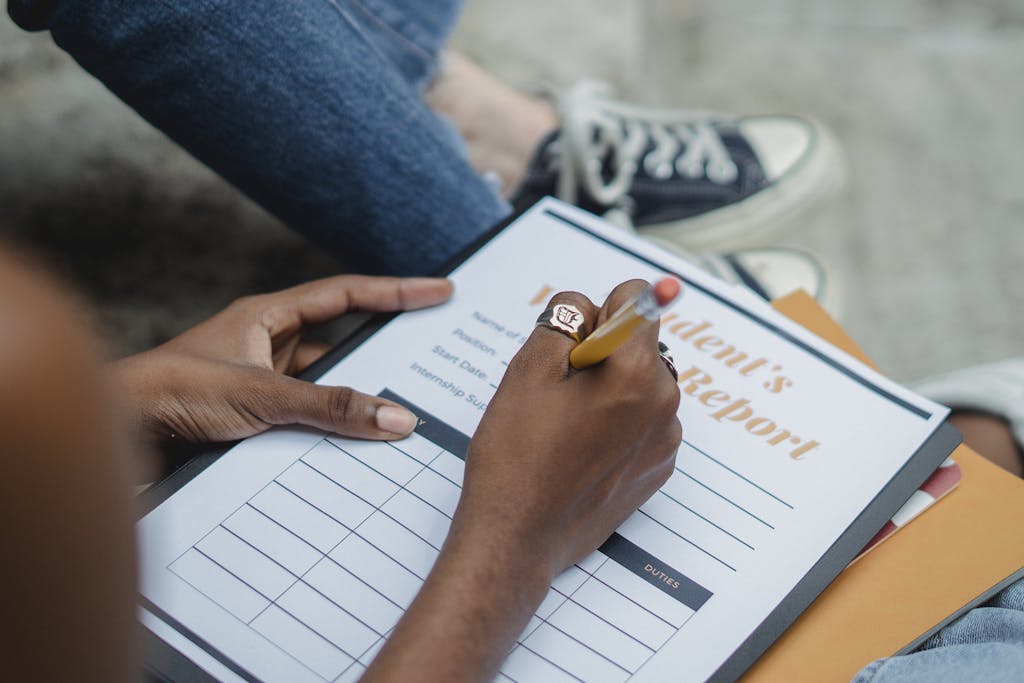 A student diligently writes on a report form outdoors while focusing on the task.